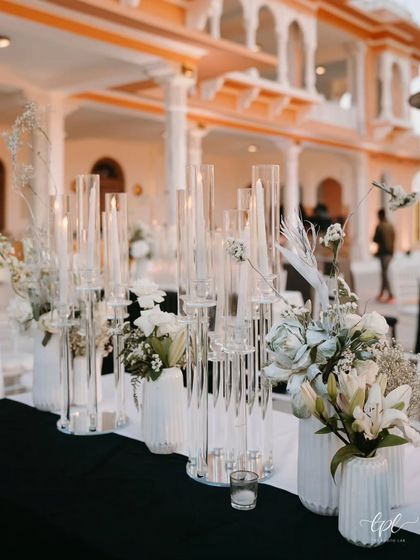 The dining tables at the black-and-white sangeet featured tall glass candle holders and white floral arrangements. This created a beautiful contrast against the black tablecloths, adding to the elegant and modern aesthetic.