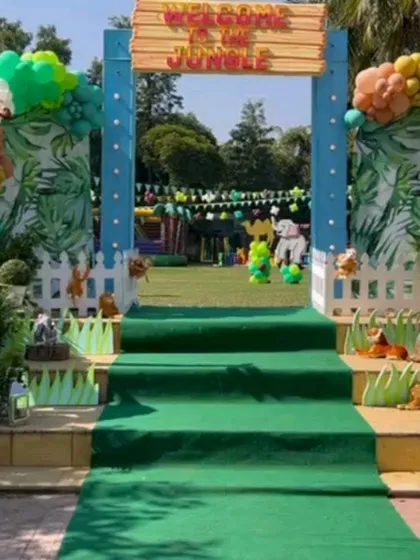 A "Welcome to the Jungle" entrance for an outdoor party, with a green carpet runner leading guests into the celebration.