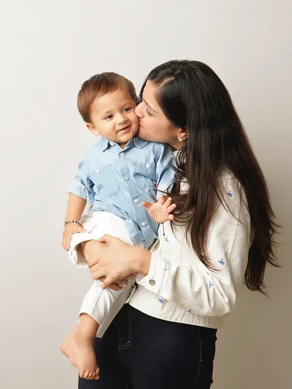 A mother gives her son a sweet kiss on the cheek. His happy expression shows the love and comfort he feels in her arms.