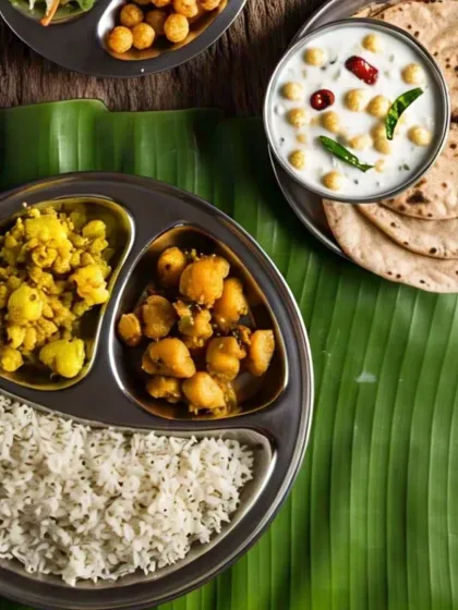 Another view of a classic homestyle thali, with fluffy rice, two types of sabzi, boondi raita, and soft rotis, served on a banana leaf for an authentic touch.