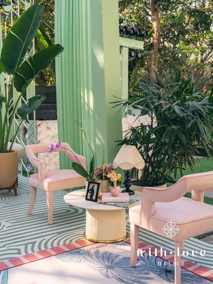 A cozy seating nook in 'The Conservatory', with plush pink chairs and a modern side table.