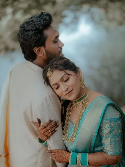 An intimate moment between the couple. The bride, in her beautiful South Indian attire, rests her head on the groom's shoulder.