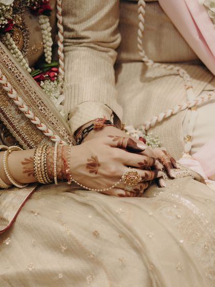 A detail shot of the bride's hands, adorned with mehendi, bangles, and a statement ring, all part of her curated look.