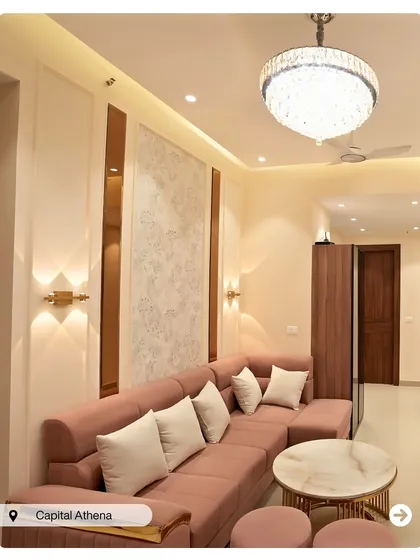 A soft and inviting living room at Capital Athena. The dusty rose sofa, marble-top coffee table, and textured wall panel create a chic and contemporary feminine space.