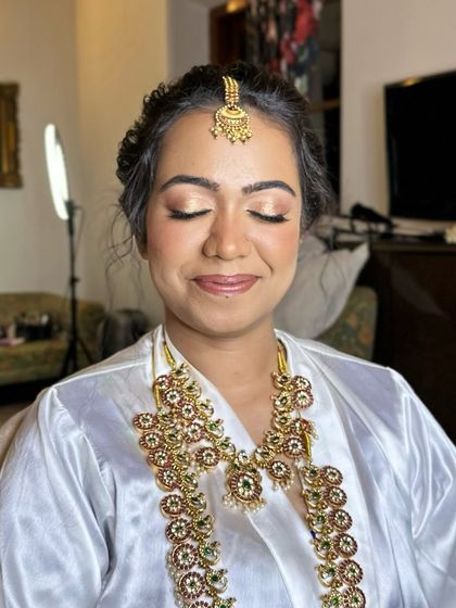 A pre-drape shot, showing the radiant makeup and hairstyle before the saree is draped, highlighting the flawless base.