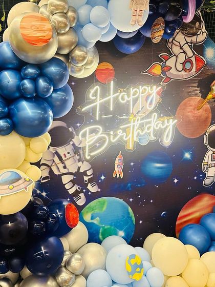A close-up of the out-of-this-world space-themed birthday decoration, showing the detailed planet and astronaut balloons against the galaxy backdrop.