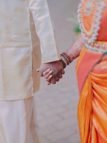 A close-up shot of the couple holding hands, a simple yet powerful symbol of their union. The details of the bride's bangles and mehndi add to the story.