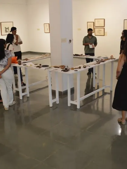 A group of visitors gathers around the installation tables as the artist, Mohit Mahato, gives a walkthrough of his work.