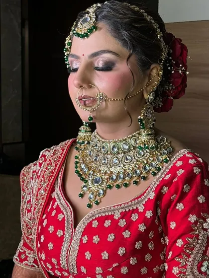 A close-up of a classic North Indian bridal makeup look. The focus here is on the detailed eye makeup with a silver and black smokey effect, perfectly complementing the heavy kundan and emerald jewelry.