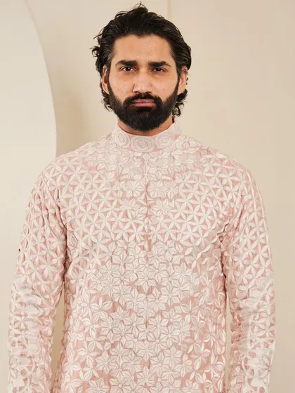 A portrait in the blush pink kurta, showing the detailed embroidery around the mandarin collar.