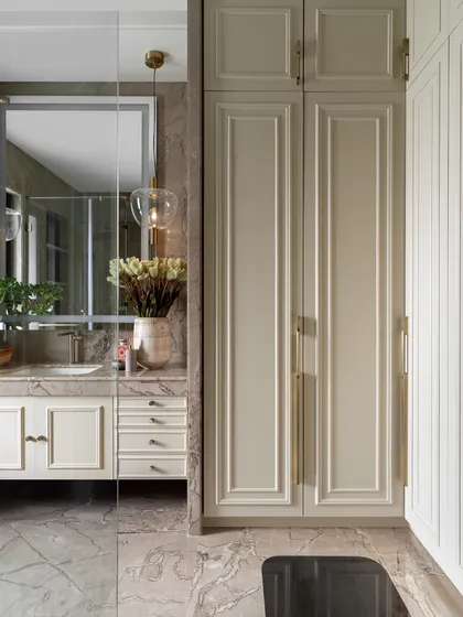 A classic and timeless bathroom design in the Juneja Residence. The warm beige tones of the cabinetry and the rich veining of the marble floor create a sophisticated and serene atmosphere.