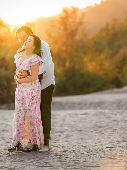 A moment of pure bliss. The sun's flare catches her hair as she leans back into his embrace, a perfect candid shot filled with warmth and affection.