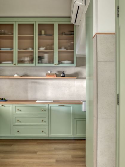 The kitchen was retrofitted into a small, preexisting room, so we focused on maximizing every inch. A light mint green color for the cabinetry and taking storage to the ceiling helps the compact space feel bright and spacious.