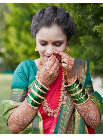 A detailed shot focusing on the beautiful elements of a traditional bridal look, from the intricate henna on her hands to the delicate nose ring and gold jewelry.