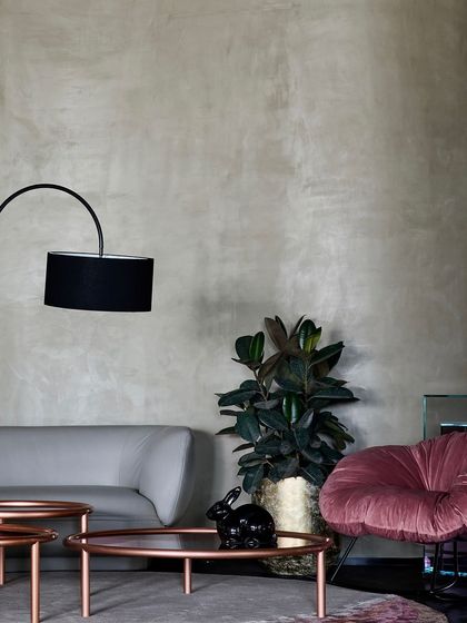 This vignette in the Ventura showroom combines a sleek modern sofa with a plush, velvet armchair. The lime-washed walls provide a neutral, textured backdrop for the furniture.