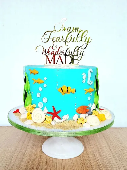An underwater-themed cake with a simple buttercream base. The details are made with crushed biscuits for sand and fondant sea creatures.