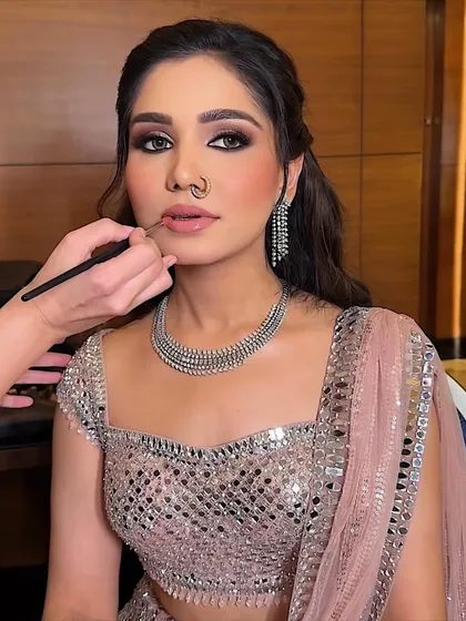 Final touches on a smokey eye and nude lip combination. The nose ring adds a traditional touch to this modern, glamorous party look.