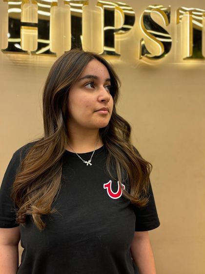 A client looking confident with her new balayage. The lighter pieces are strategically placed to frame her face and brighten her overall look.