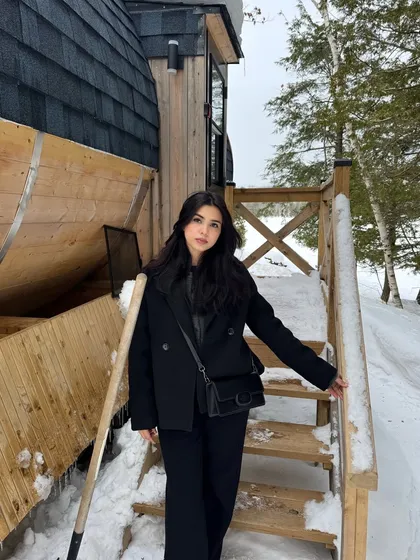 A different pose on the snowy cabin steps, showing the winter outfit from another angle.