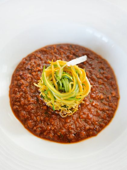 A closer look at the Chettinad chicken keema, topped with a nest of lemon and zucchini seviyan. The dish is layered with both depth and detail.