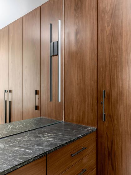 Detail of a custom wardrobe in the Parishram residence. The combination of dark wood and a black marble top, along with sleek, modern hardware, exemplifies our commitment to material honesty.