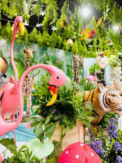 A side view of the rich safari decorations, highlighting the pink flamingos and the tiger prop emerging from the greenery.