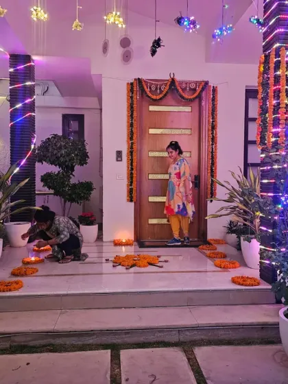 The entrance to a home for a Guruji Satsang, decorated to welcome guests into a spiritual space. I used traditional marigold garlands, fairy lights wrapped around the pillars, and earthen diyas to create a warm and inviting pathway.