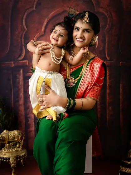 A sweet and happy portrait of a mother holding her smiling baby Krishna. The genuine smiles and traditional attire make this a perfect Janmashtami keepsake.