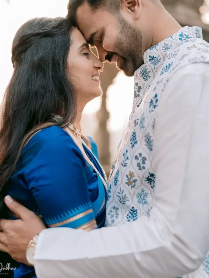 An intimate close-up filled with warmth and affection. The soft light highlights the couple's gentle smiles and the intricate details of their traditional attire.