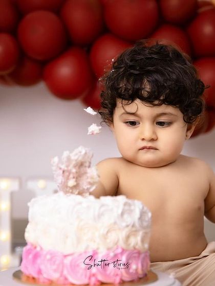 A close-up of the cake smash action, with frosting-covered hands and a look of intense focus.