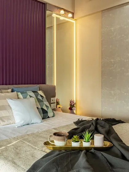 Another angle of the master bedroom, showing the interplay between the purple fluted wall panel, the soft bedding, and the warm light from the dressing mirror.