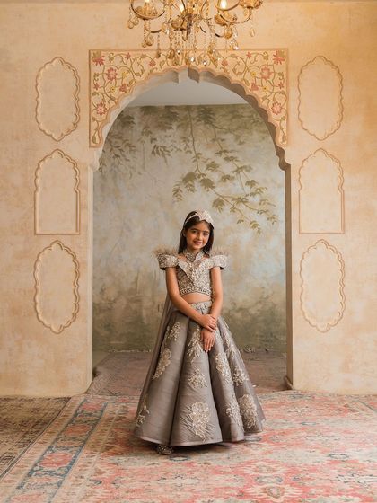 A full length view under a chandelier, this grey lehenga set is the definition of royal elegance for a young girl.