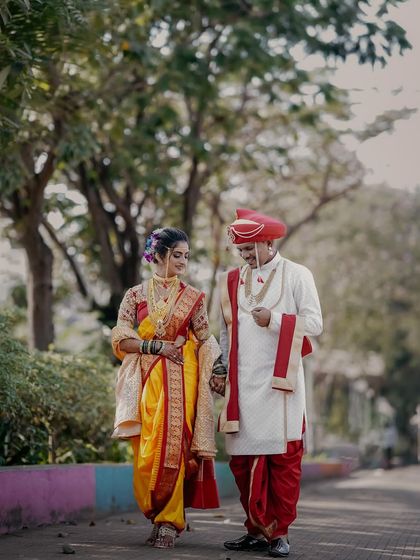 A candid shot of the couple walking hand-in-hand. This photo captures the beginning of their journey together, dressed in beautiful, traditional Maharashtrian wedding attire.