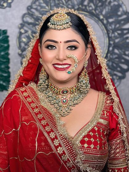 A classic portrait of a bride in a red lehenga, with beautiful golden glittery eyes and a matching red lip. The traditional jewellery completes this timeless look.