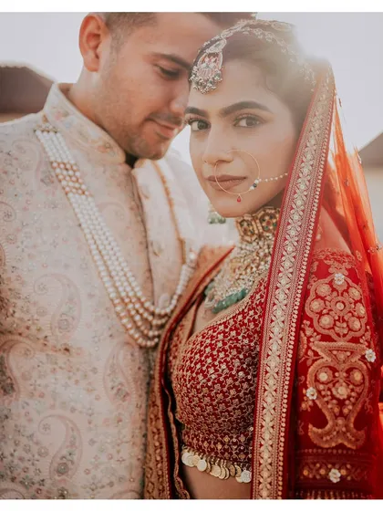 A striking portrait where the bride looks directly at the camera while the groom stands closely behind her.