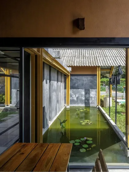 A view from the Teyla cafe seating area, looking out across a lily pond towards the covered walkway, blending the built environment with natural elements.