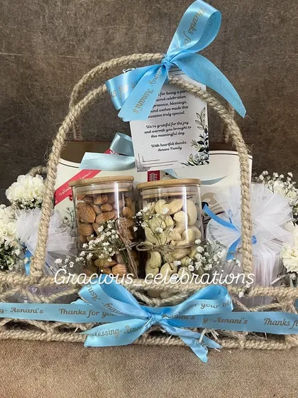 A perfect example of a premium housewarming return favor. This elegant jute basket includes jars of high-quality dry fruits, fresh baby's breath flowers, and a custom-printed ribbon with a thank you message from the family. It's a warm and welcoming gift for guests.