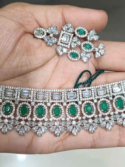 A detailed American Diamond choker with a mix of baguette and round-cut stones, accented with oval green stones.