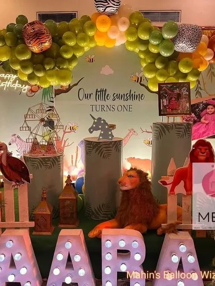 A closer look at the details of the "Little Sunshine" jungle party, showing the layered props, including a lion, lanterns, and a white picket fence that adds a charming touch.