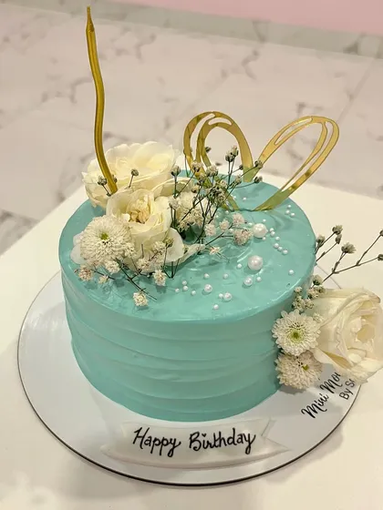 Another angle of this beautiful floral birthday cake. The combination of the textured frosting, fresh flowers, and gold accents makes it a sophisticated choice for any celebration.