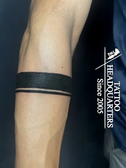 A solid black armband with a thin parallel line, a classic, bold, and minimalist design.