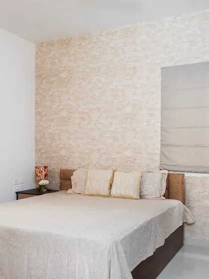 Soft neutrals and cozy textures create a bedroom that feels calm and inviting. The textured wallpaper adds depth without overwhelming the space.