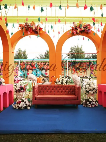 The main stage of the carnival-themed Mehendi, featuring bright orange arches and whimsical flamingo props.