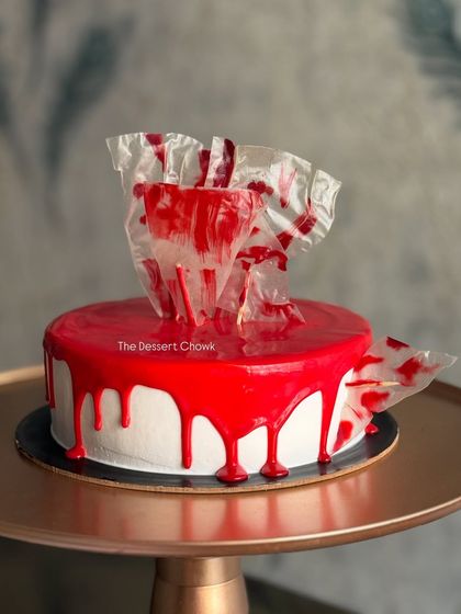 A modern and artistic take on the chocolate truffle cake, with a glossy red glaze and abstract chocolate shard topper.