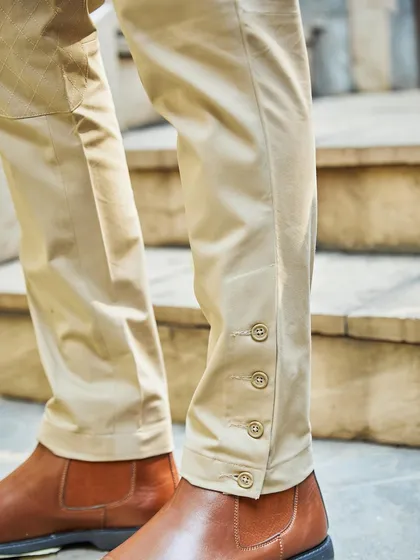 A focus on the details of the beige breeches, featuring button closures at the ankle. It's these small, thoughtful touches that define my bespoke tailoring.