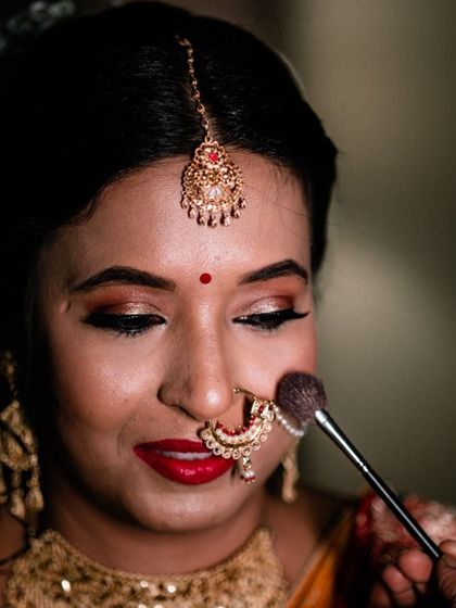 A getting-ready shot where the makeup artist applies a final touch of powder. We capture these details to show the care that goes into your bridal look.