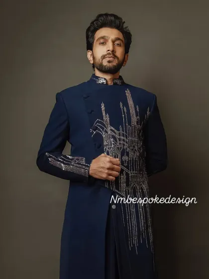 This navy blue asymmetrical indowestern features abstract architectural embroidery in silver thread. It's a sophisticated and unconventional choice for a modern groom.