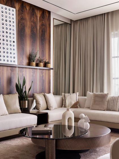 This shot captures the elegant layering of textures in the living room, from the soft sofa to the smooth finish of the coffee table and the rich grain of the wood-paneled wall.