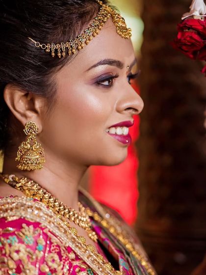 A side profile showcasing the flawless base and the intricate Jhumka earrings. I always pay close attention to how the makeup, hair, and jewelry come together.