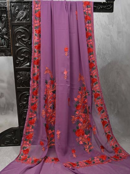 A lovely lavender georgette saree with red and orange floral embroidery. The soft, flowing fabric and beautiful design make it a graceful choice for parties.